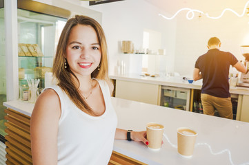 Beauty portrait of young women enjoy coffee in coffee shop on wooden table. Fascinating fashion model posing