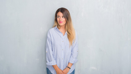 Young adult woman over grey grunge wall wearing fashion business outfit smiling looking side and staring away thinking.