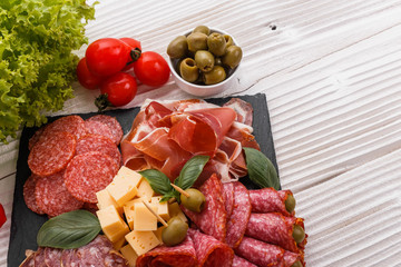 Cold smoked meat plate on a rustic wooden background