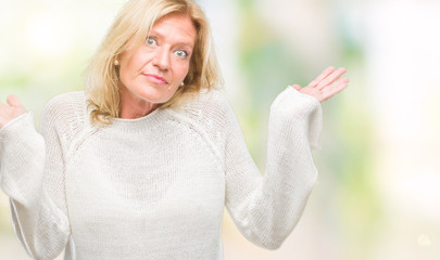 Middle age blonde woman wearing winter sweater isolated background clueless and confused expression with arms and hands raised. Doubt concept.