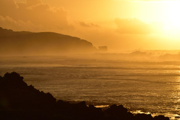 朝焼けと煙のような波しぶき