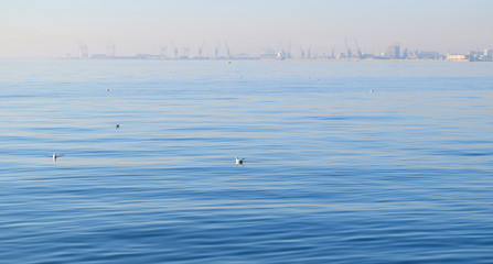 Calm blue sea at Thessaloniki seafront. Old harbour background in the mist. 