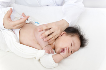 Obraz na płótnie Canvas 医師(看護師)により腕に注射を打たれ泣いている新生児の赤ちゃん。予防接種、インフルエンザ、病気、治療イメージ