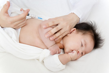 Fototapeta na wymiar 医師(看護師)により腕に注射を打たれ泣いている新生児の赤ちゃん。予防接種、インフルエンザ、病気、治療イメージ