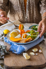 Woman hands holds steamed cooked assorted vegetables. Carrots, pumpkin, roasted potato, onion rings, broccoli. Seasonal vegan lunch, vegetarian autumn dinner, healthy food. With herbs, spices.