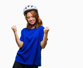 Young beautiful woman wearing cyclist helmet over isolated background very happy and excited doing winner gesture with arms raised, smiling and screaming for success. Celebration concept.