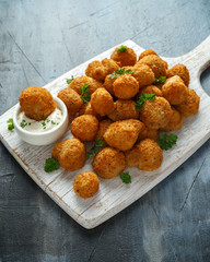 Homemade Breaded Garlic Mushrooms with sour cream and parsley on white wooden board