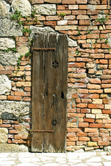 Old wooden door in old brick wall, Italy