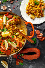 Traditional paella in the fry pan with chicken, prawns, spicy chorizo, lemon and glass of white...