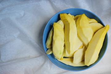 Peeled ripe mango on blue dish.