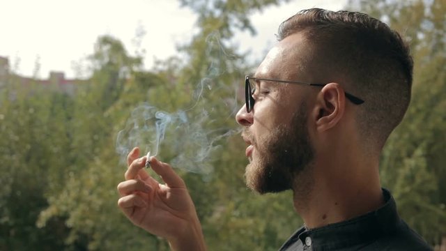 Man smoking a rolled up cigarette. Man smoking a joint with tobacco