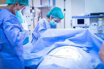 Team of surgeon in uniform perform operation on a patient at cardiac surgery clinic.