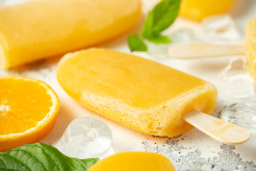 Popsicles, ice lollies on stick with sweet orange juice on white background with ice