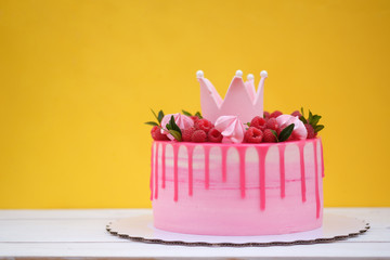pink cake with crown on birthday on yellow background