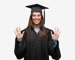 Young hispanic woman wearing graduated cap and uniform showing and pointing up with fingers number ten while smiling confident and happy.