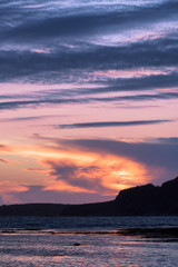 Sunset over Rocky Harbour in Newfoundland with the Lobster Cove Lighthouse in the distant background