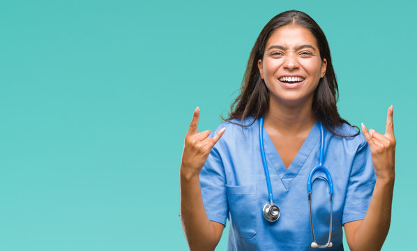 Young arab doctor surgeon woman over isolated background shouting with crazy expression doing rock symbol with hands up. Music star. Heavy concept.