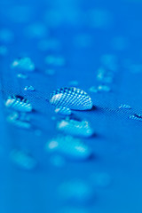 Rain water droplets on  blue waterproof fabric  background