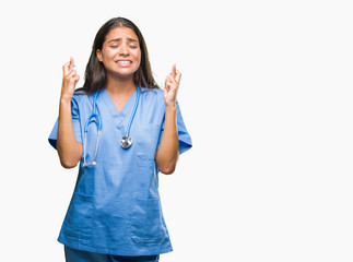 Young arab doctor surgeon woman over isolated background smiling crossing fingers with hope and eyes closed. Luck and superstitious concept.