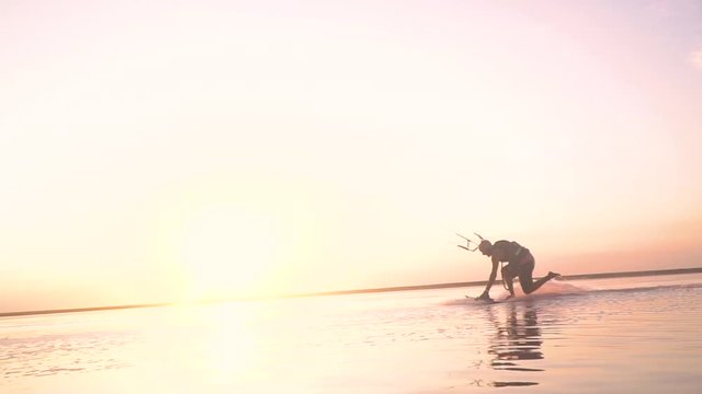 The man performs tricks on the wakeboard and controls the training kite