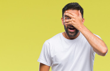 Fototapeta na wymiar Adult hispanic man over isolated background peeking in shock covering face and eyes with hand, looking through fingers with embarrassed expression.