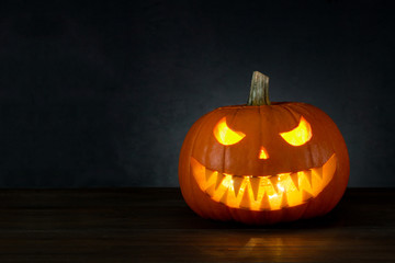 Halloween background. Pumpkin Jack O'Lantern head with candle light with copy space on dark background
