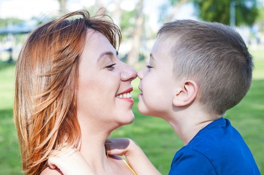 Young and beautiful Caucasian woman and her son touching each other nose to nose, face to face close up portrait, mother child love family concept. Look at each other. Single mother.