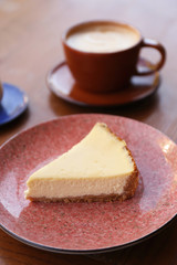 Plate with slice of cheesecake on wooden table