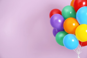 Fototapeta na wymiar Bunch of bright balloons and space for text against color background