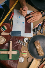 High angle view of caucasian male hand master cutting with a knife pattern from genuine leather....