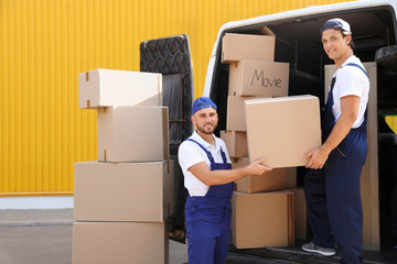 Male movers unloading boxes from van outdoors