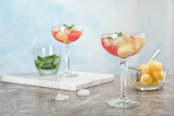 Glass with tasty watermelon and melon ball drink on table