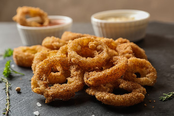 Homemade crunchy fried onion rings on slate plate, closeup