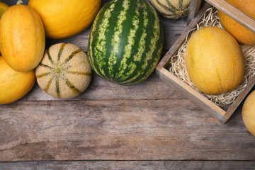 Ripe melons and watermelon on wooden background, flat lay. Space for text
