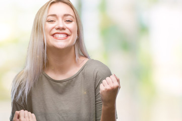 Young blonde woman over isolated background very happy and excited doing winner gesture with arms raised, smiling and screaming for success. Celebration concept.