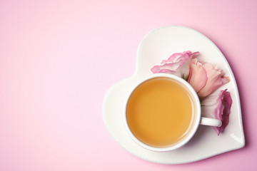 Cup of tea and flowers on color background, top view with space for text