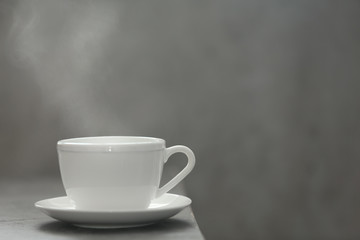 Cup of tea and saucer on table against gray background