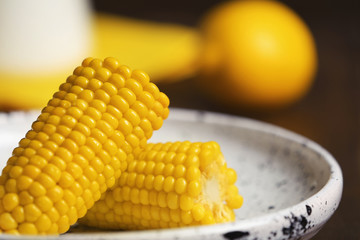 Plate with ripe corn cobs on blurred background, closeup