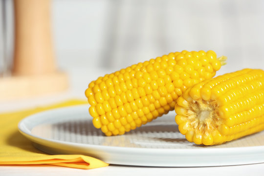 Plate with ripe corn cobs on table, closeup