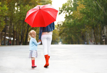 Mother and daughter with red umbrella on street