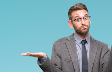 Young handsome business man over isolated background clueless and confused expression with arms and...