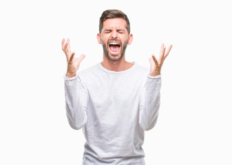 Naklejka premium Young handsome man over isolated background celebrating mad and crazy for success with arms raised and closed eyes screaming excited. Winner concept