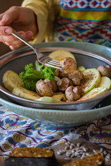 Woman hands prick on fork steamed, cooked, baked and roasted organic assorted vegetables with paprika, herbs, oregano. Zucchini, mushrooms. Vegan lunch, vegetarian dinner, healthy food