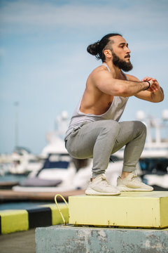 Extreme Jump Squats Fitness Training. Crossfit Athlete Caucasian Man Doing High Jump Squat Exercise Workout On Makeshift Box At The Marina Summer Pier