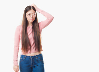Fototapeta premium Young Chinese woman over isolated background wearing glasses confuse and wonder about question. Uncertain with doubt, thinking with hand on head. Pensive concept.