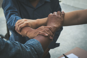 Team work concept; close up of joining hands of businessman in unity cross processing background;...