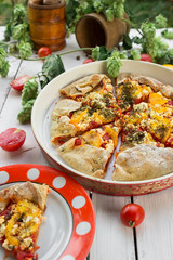 Freshly baked tomato galette. White wooden background. Style rustic. Decor. Picnic in the garden. Table setting.