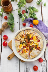 Freshly baked tomato galette. White wooden background. Style rustic. Decor. Picnic in the garden. Table setting.