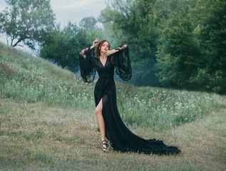 expensive free open delightful dress, bare leg, slender figure, model, fashion 2018, wonderfull lady. light queen becomes dark. orange makeup. hands near the face. standing in the clearing. art photo.