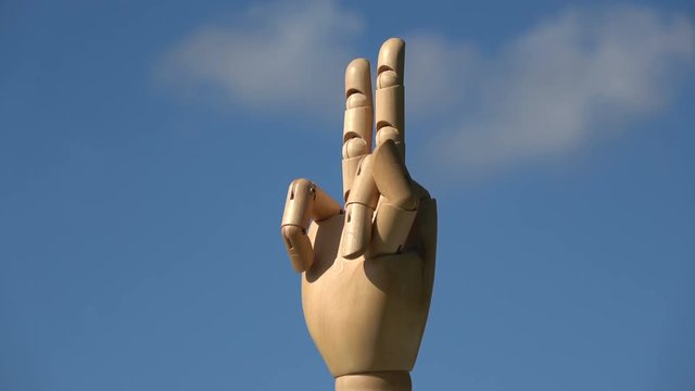Rotating wooden manikin art hand show two fingers victory gesture sign symbol